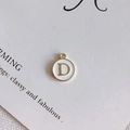 Detail of round white enamel pendant with golden letter D for DIY jewelry making - Style D
