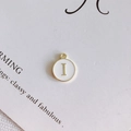 Dettaglio ciondolo rotondo in smalto bianco con lettera I dorata per gioielli DIY - Stile I