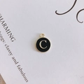 Detail of round gold metal charm with black oil drip and gold letter C for DIY jewelry - Letter C