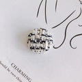 Gros plan sur un bouton en tweed pied-de-poule avec fils noirs, blancs et dorés - Style Tweed Blanc Noir Fil Doré (1#)