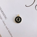 Detail of round black enamel pendant with gold letter O for DIY jewelry making - Letter O