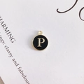 Macro detail of round alloy pendant with black enamel finish and golden letter P - Letter P