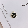 Detailed macro view of a round black enamel letter W pendant for DIY jewelry making - Letter W