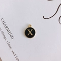 Detail view of round black enamel letter X charm with gold-plated metal alloy finish - Letter X