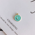 Primer plano de dije redondo dorado letra C con esmalte azul tiffany para bisutería - Letra C