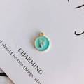 Macro view of gold letter F pendant with green enamel finish for DIY jewelry making - Letter F