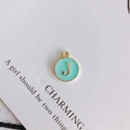 Detailed close-up of a mint green enamel round pendant with a gold letter J charm - Letter J