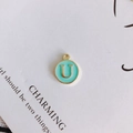 Detail of a round gold-plated alloy pendant with sky blue enamel and letter U inlay - Letter U