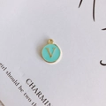 Close-up of golden round V letter pendant with light blue enamel finish for DIY jewelry - Letter V