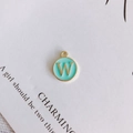 Detail of round gold pendant with mint green enamel and letter W for DIY jewelry making - Letter W