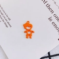 Makroaufnahme eines minimalistischen orangefarbenen Jungen-Anhängers auf Gitterstoff - Orangener Jungenstil (7#)