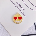 Dettaglio ravvicinato di un ciondolo emoji con occhi a cuore in smalto giallo e oro - Colore #14