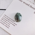 Macro shot of irregular marble-textured stone pendant on minimalist card with poem - 4#