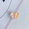 Gros plan d'un accessoire pour cheveux papillon en résine avec détails jaune et rose - Orange