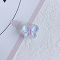 Détail d'un accessoire papillon en résine avec finition colorée bleue et rose - Bleu clair
