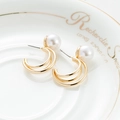 Nahaufnahme eleganter goldener Mehrschicht-Ohrringe mit weißen Perlen auf einer Schale - Dreifach-Reifen Große Perle / Large Pearl Style C