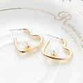 Elegante gouden hartvormige oorbellen met parels op een decoratief bord gepresenteerd - Gouden Groot Hart Parel / Hart Stijl B