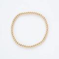 Vista detallada de una pulsera elástica minimalista de cuentas doradas sobre blanco - Dorado