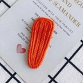 Macro detail of orange knit hair clip featuring a textured herringbone weave pattern - Orange