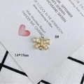 Detalle macro de un colgante de lazo dorado con perlas blancas y bucles de enganche dobles - Estilo de Lazo Pavé de Perlas Artificiales (8#)