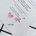 Detalle macro de un colgante de lazo dorado 10x14mm con textura de cuerda en tarjeta blanca - Estilo de Lazo con Detalle de Torsión (12#)
