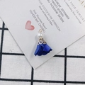 Détail d'un pendentif fleur en tissu bleu foncé avec base dorée et perle blanche - Bleu Foncé