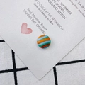 Detailaufnahme einer farbenfrohen gestreiften Glasperle auf Vintage-Hintergrund für DIY - Orange Cyan Weiß Gestreift (4#)