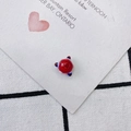 Detailed shot of a red glass bead pendant with blue and white stripes on a checkered background - Red and Blue Stripe Sphere Style (4#)