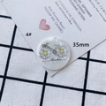 Macro-opname van een 35mm acryl hanger met een avontuurlijke fiets en madeliefjes detail - Rond 35mm / Witte Fiets "Adventure" (4#)