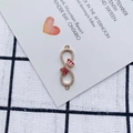 Macro detail of infinity gold pendant with red bow gemstone and crystal pavé accents - Rose Pink Style (2#)