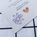 Vista macro di graffetta in metallo lilla a forma di margherita su carta decorativa - Lavanda