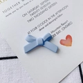 Macro view of light blue matte bow accessory on white display card with plaid background - Light Blue