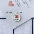 Dettaglio macro del ciondolo a forma di rosa smaltata 21x18mm per creazione gioielli - Fiore Rosso Foglia Verde Base Bianca Bordo Dorato Stile Rotondo (9#)