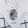 Vista macro del dije de arcilla gris de 45x39mm con vibrantes flores de colores - Estilo Ovalado Gris Flores Coloridas (6)