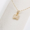 Dettaglio macro del ciondolo dorato lettera M con zirconi brillanti e catena lucida - Lettera M