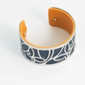 Modern silver cuff bracelet with blue leaf cutout and bright orange leather lining - Blue