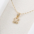 Dettaglio macro della collana con ciondolo lettera X dorata con zirconi cubici scintillanti - Lettera X