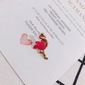 Close-up of golden flamingo pendant with pink enamel wings on decorative stationery - Rose Red (Left)
