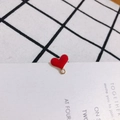 Macro detail of a red enamel heart charm with a gold metal loop for DIY jewelry making - Red