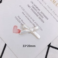 Close-up of pearl white bow charm with dimensions 33x20mm on a stylish plaid fabric - Bowknot (3)