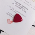 Macro shot of polished burgundy resin triangle charm on aesthetic stationery background - Dark Red