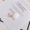 Gros plan d'un accessoire de bijoux ovale blanc poli sur une carte décorative - Blanc