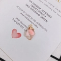 Detail of pink crystal pendant with gold bail and heart charm on white card - Transparent Pink
