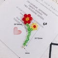 Detailed macro view of handmade crystal flower charm with red beads and green stem - Red Yellow Woven Flower With Gold Ring (6#)