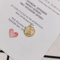 Detailed view of an 18K gold plated brass zodiac charm on a wedding card background - Virgo