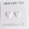 Paire de boucles d'oreilles cœur en résine blanc mat sur une carte blanche minimaliste - Blanc Pur