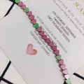 Macro detail of iridescent heart-shaped hematite beads with metallic chameleon gradient finish - Green Pink