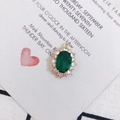 Detailed view of an oval emerald green gemstone pendant with a gold setting and white zircon - Dark Green