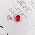 Détail d'un pendentif ovale en pierre rouge avec monture dorée et accents de zircone - Rouge