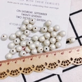 Perline bianche crema per gioielli fai-da-te mostrate su un panno a scacchi bianco e nero - 8mm / Perlina Color Caramello (KP2917-6) / Avorio